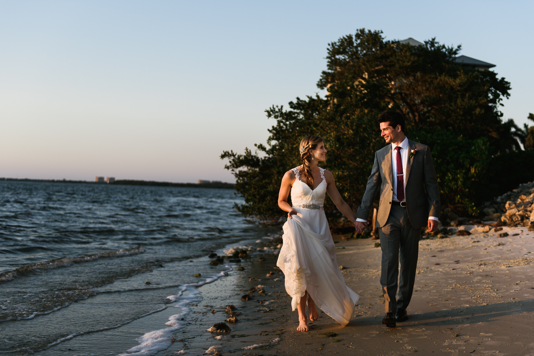 sanibel bride and groom walk beach at sunset