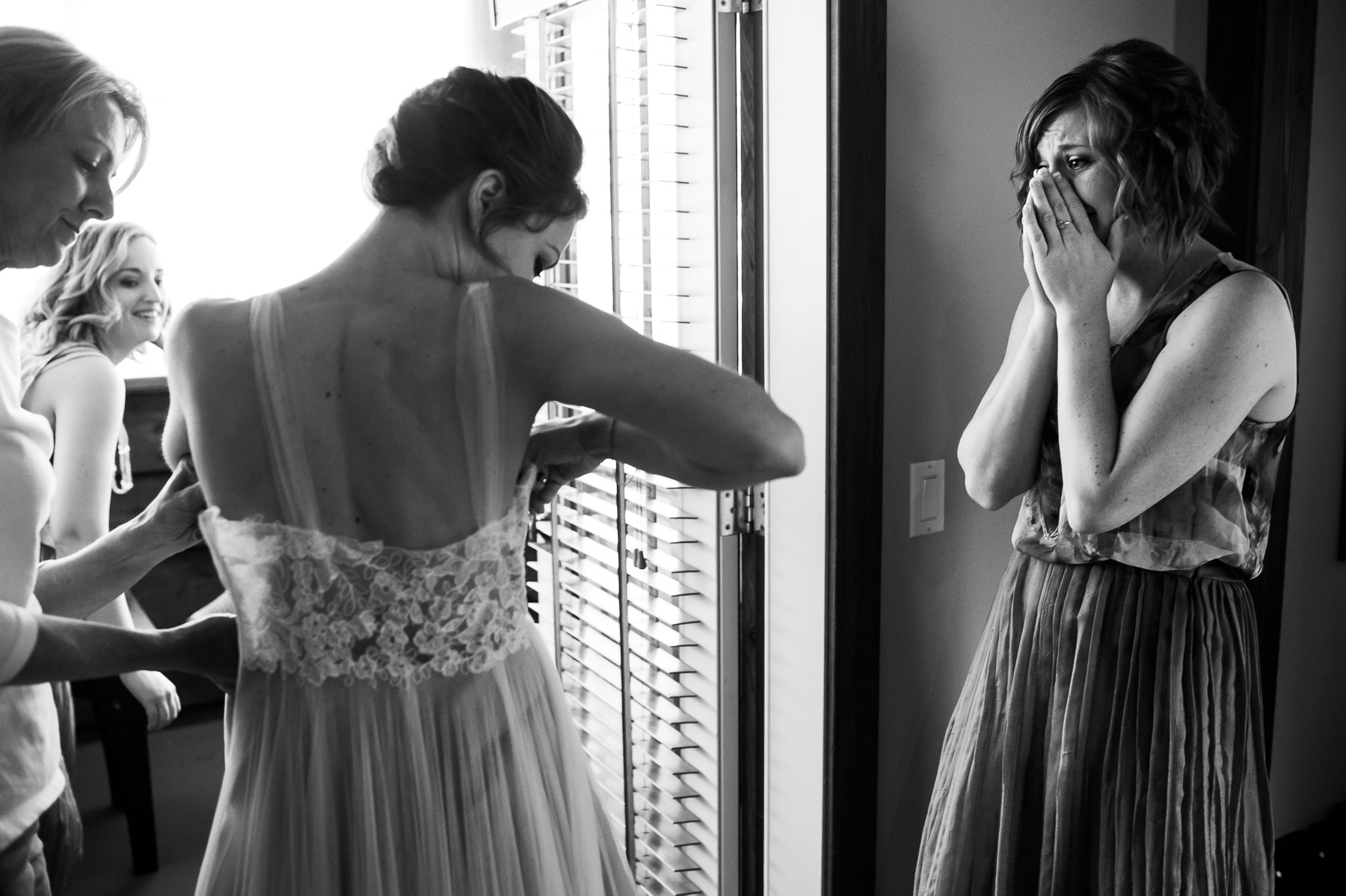 bridesmaid crying as bride gets in dress