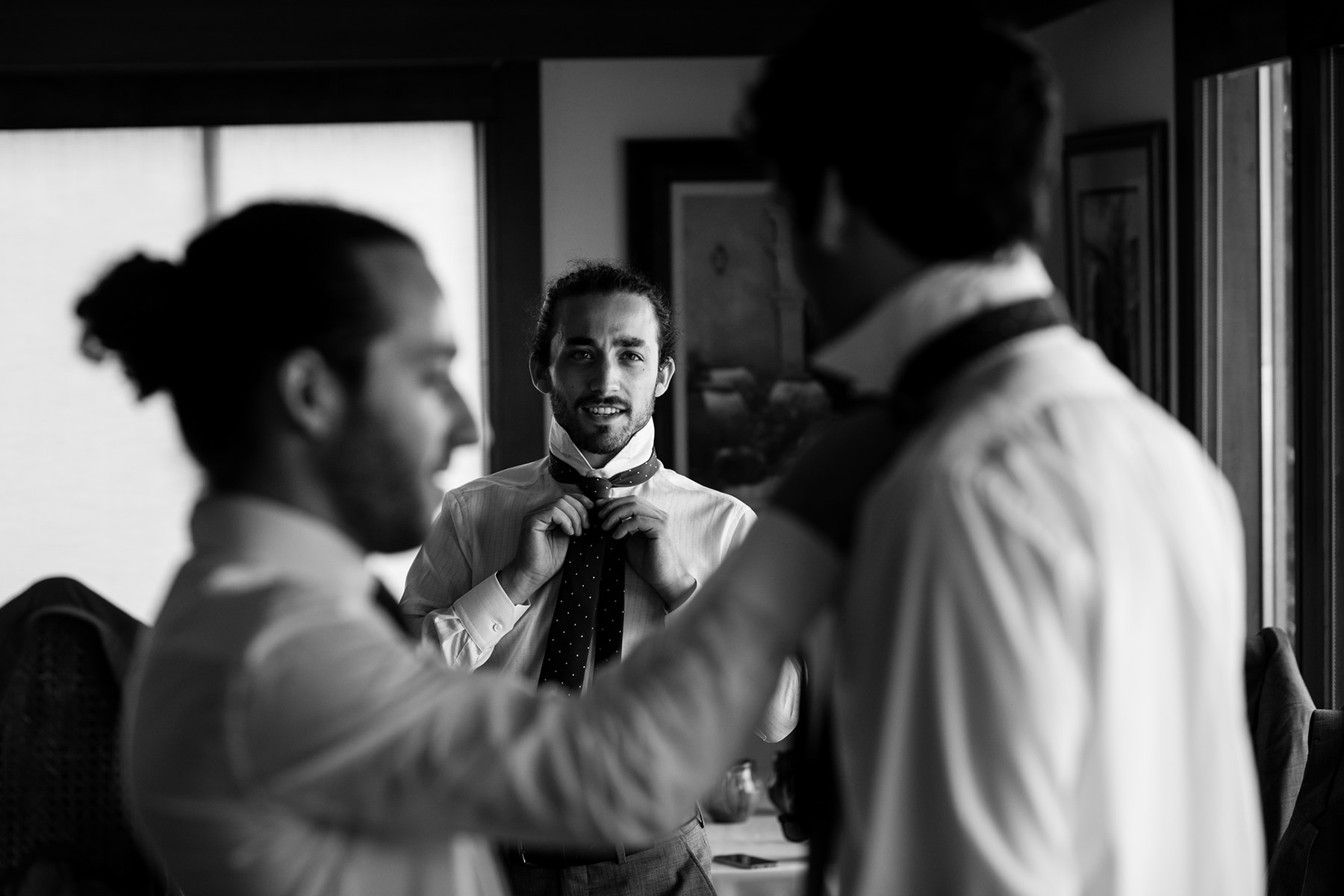 groomsmen putting ties on each other 