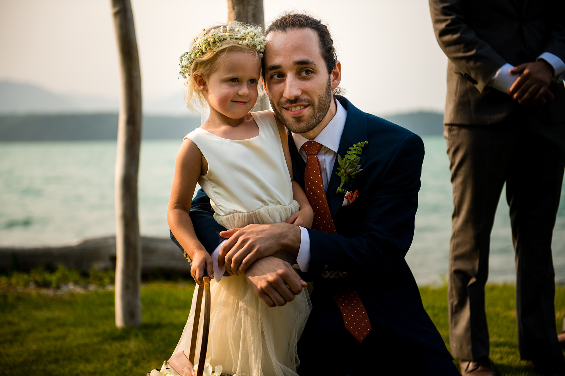 groom watching bride come down aisle with flower girl 