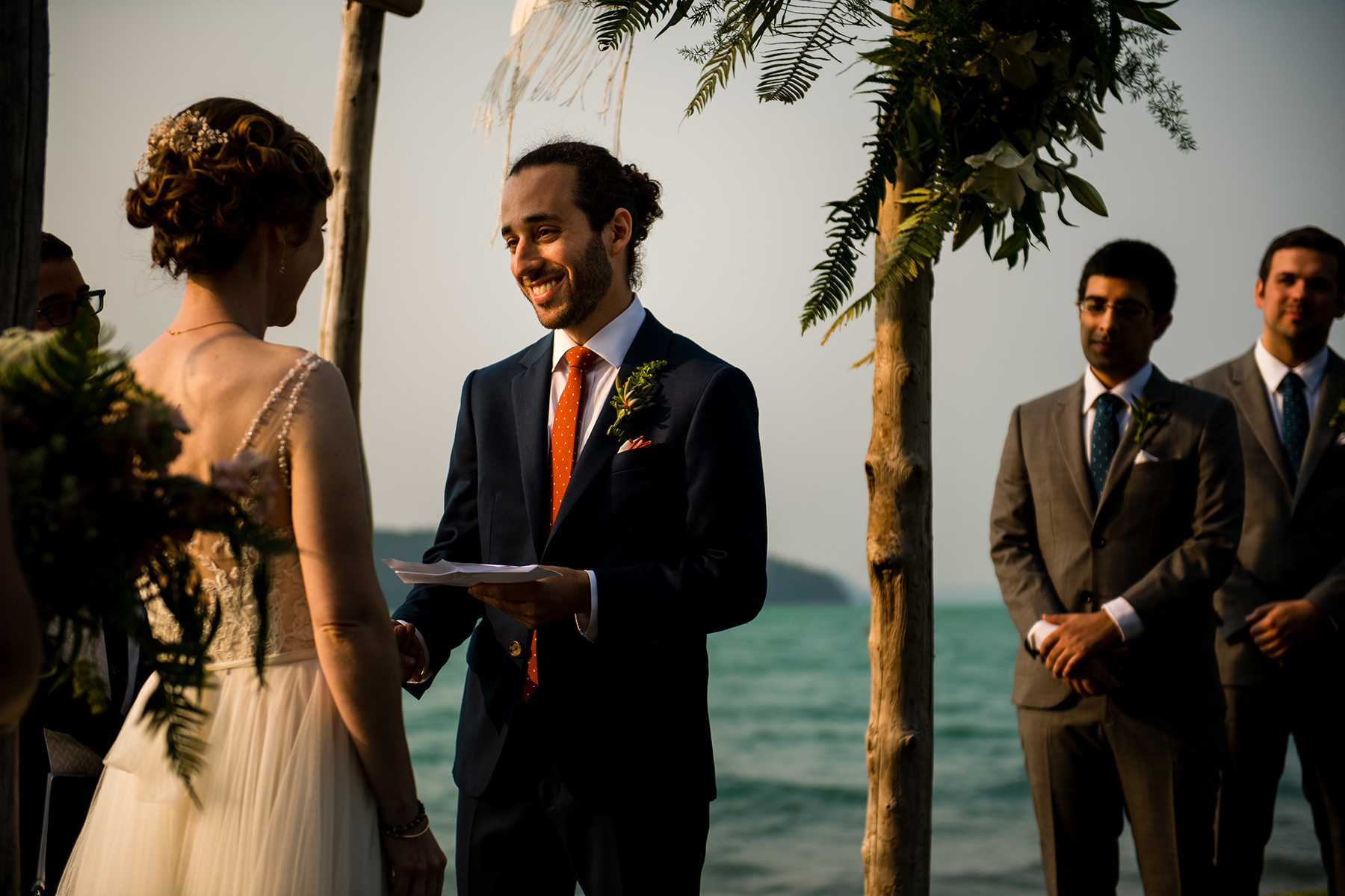 groom smiling while reading his vows