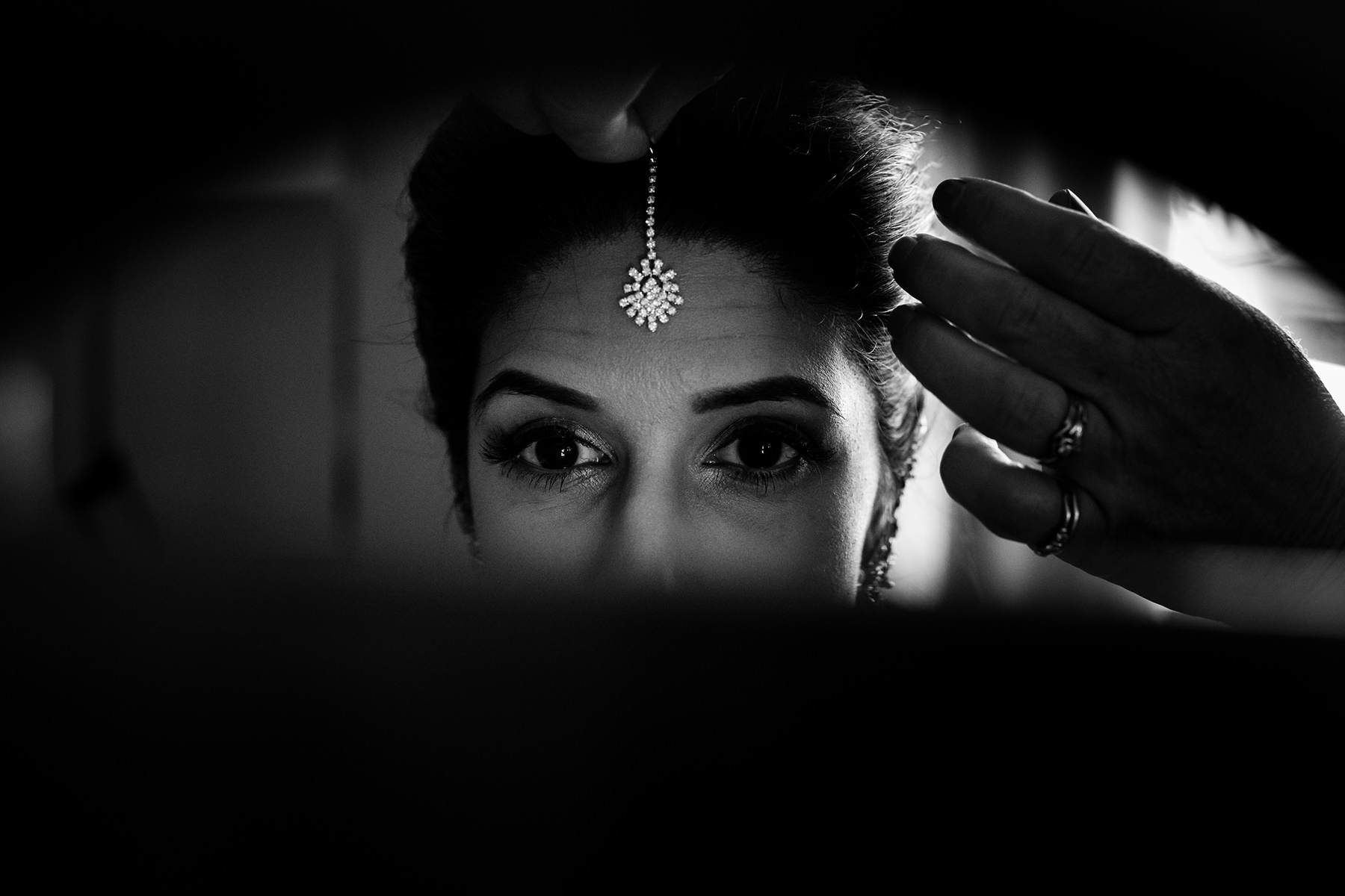 bride putting on tikka forward jewelry 