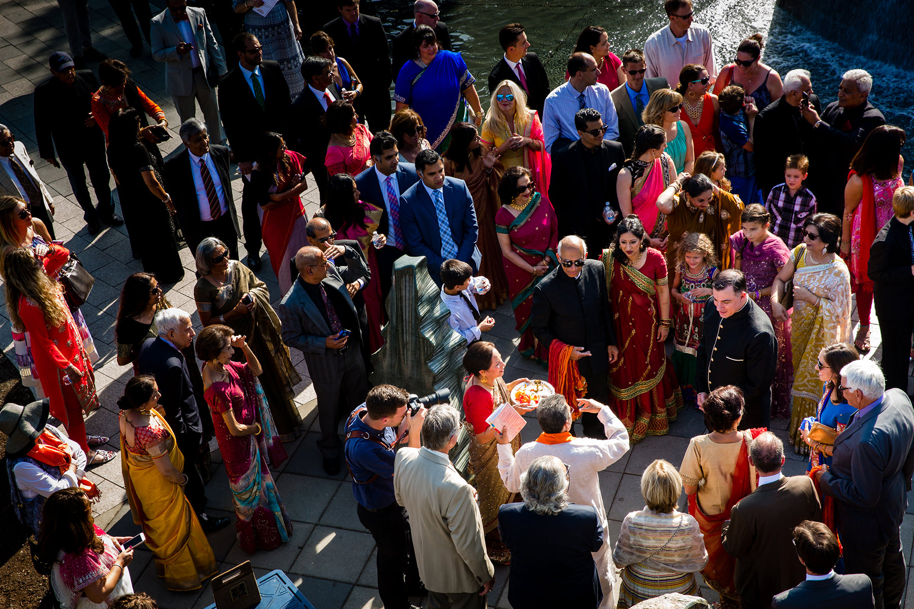family gather around groom during start of hindu wedding ceremony